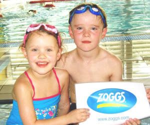 Two young swimmers holding Zoggs sign