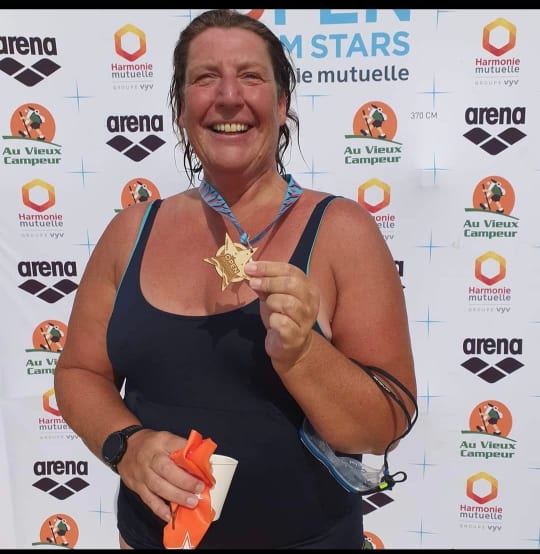 Judi in her swimming costume holding a medal