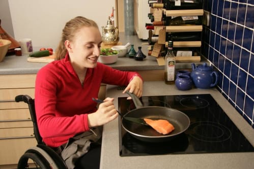 Woman in wheelchair cooking fish