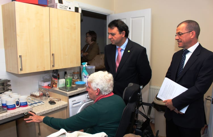 Resident showing Alberto Costa MP the accessible kitchen, with Brian Carlin