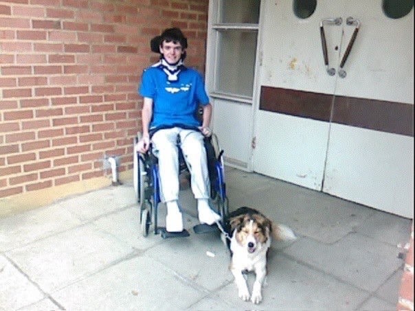 Tom in a wheelchair outside his house with his dog