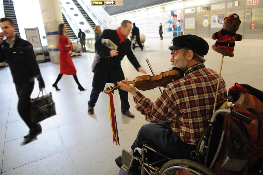 Man in wheelchair playing violin at a train station 