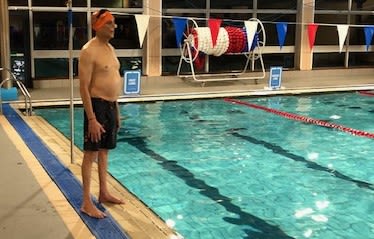 Ramesh standing by a swimming pool in his Aspire Channel Swim hat