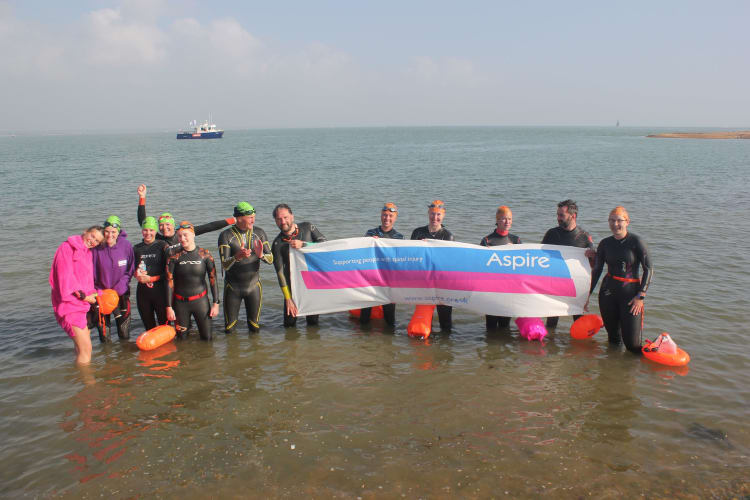 Swimmers standing in the water with Aspire banner