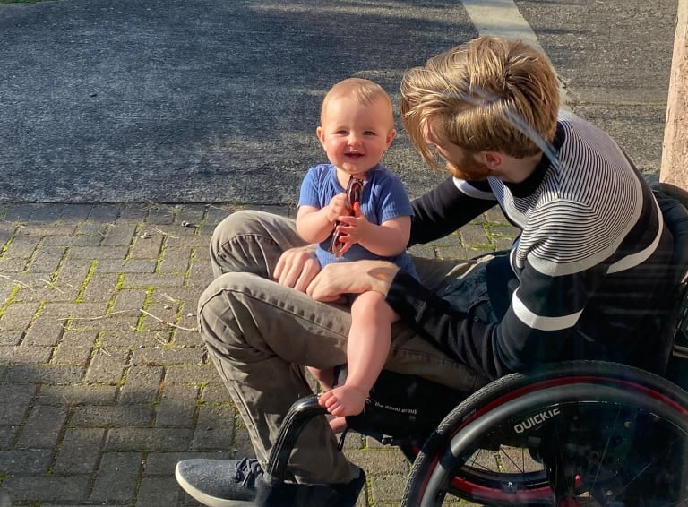 Will in his wheelchair with his daughter on his lap
