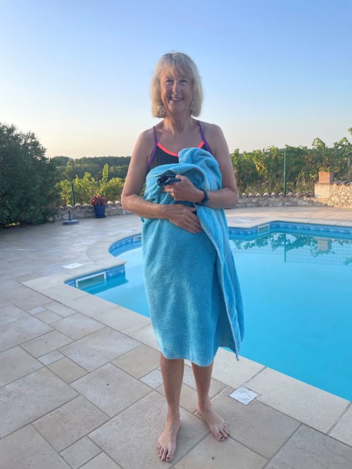 Moira standing by the swimming pool wrapped in a towel