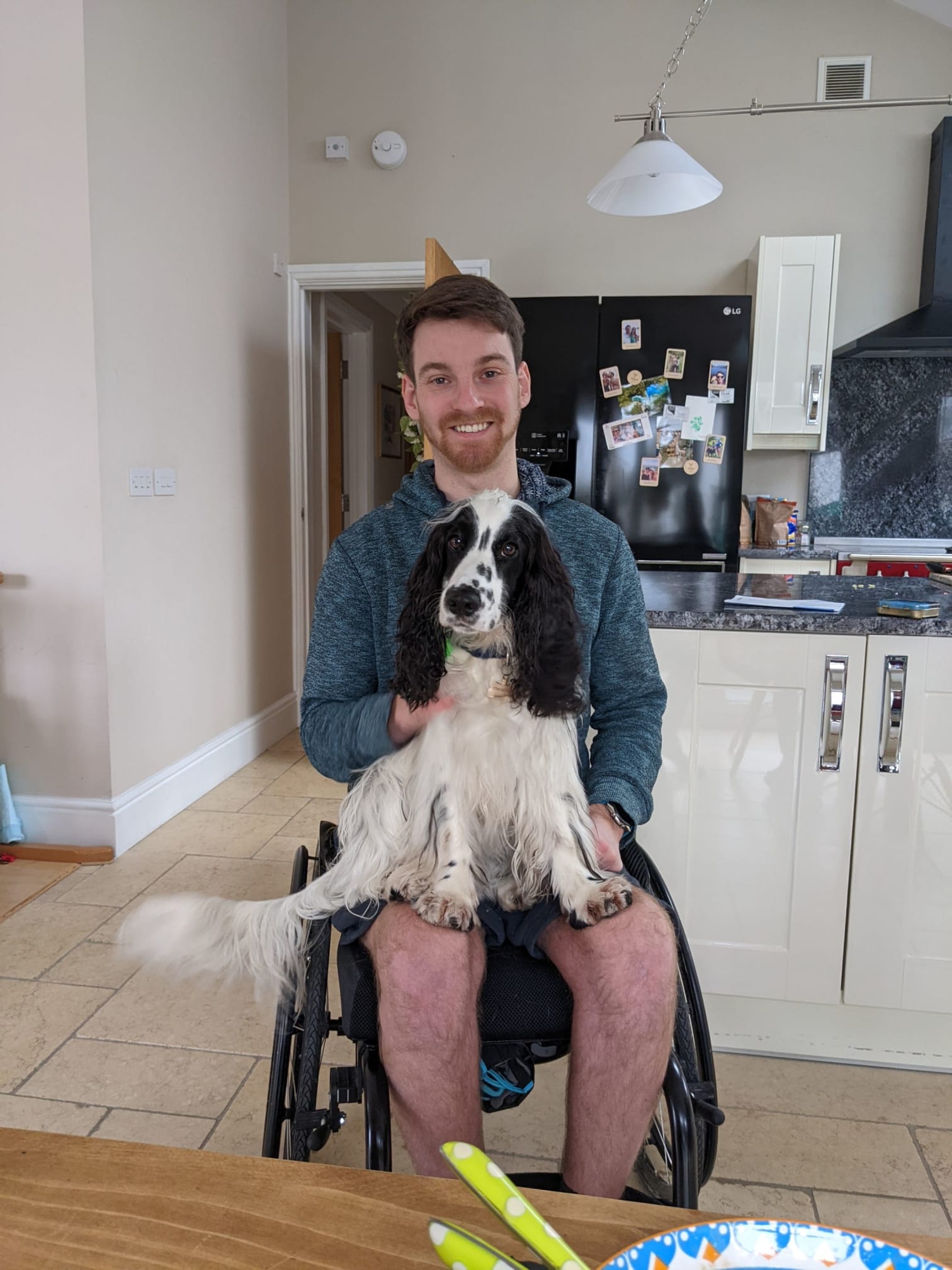Dale sitting in his wheelchair with a dog on his lap