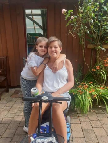 Jo on her scooter with her daughter standing next to her