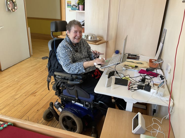 Ann in her wheelchair at her desk using a computer