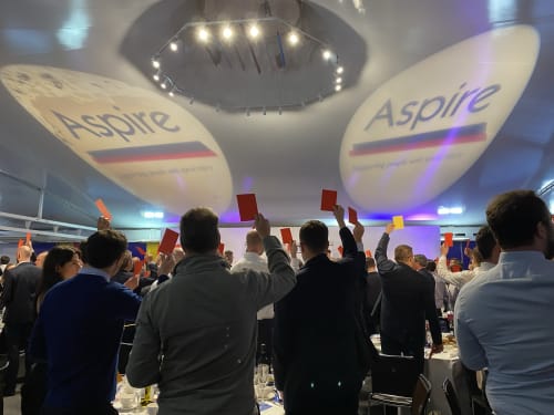 Guests holding up heads and tails cards at the London Sports Quiz Dinner