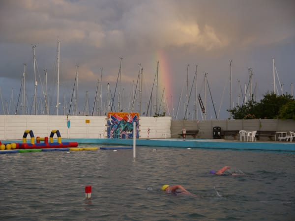 Swimmers at dusk with rainbow