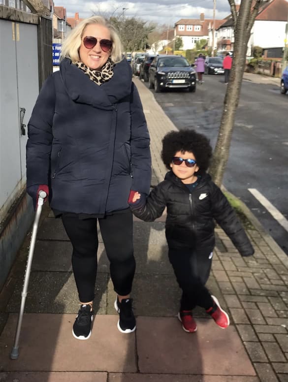 Holly walking with a crutch with her son