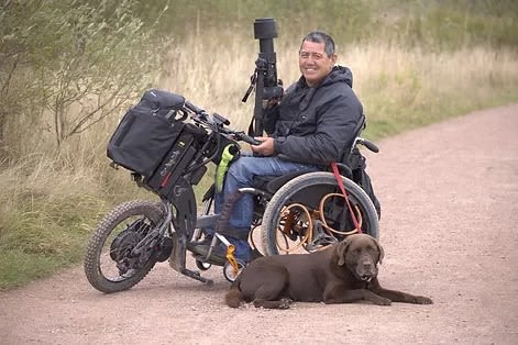 Peter in his outdoor wheelchair with his dog by his side